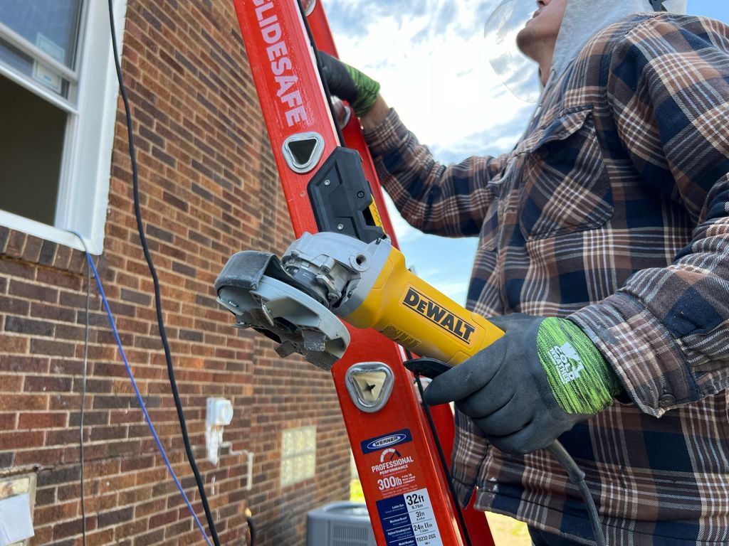 Painter prepping brick and trim with a ladder